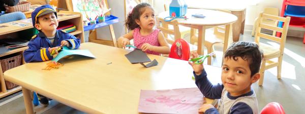 kids cutting paper around a table